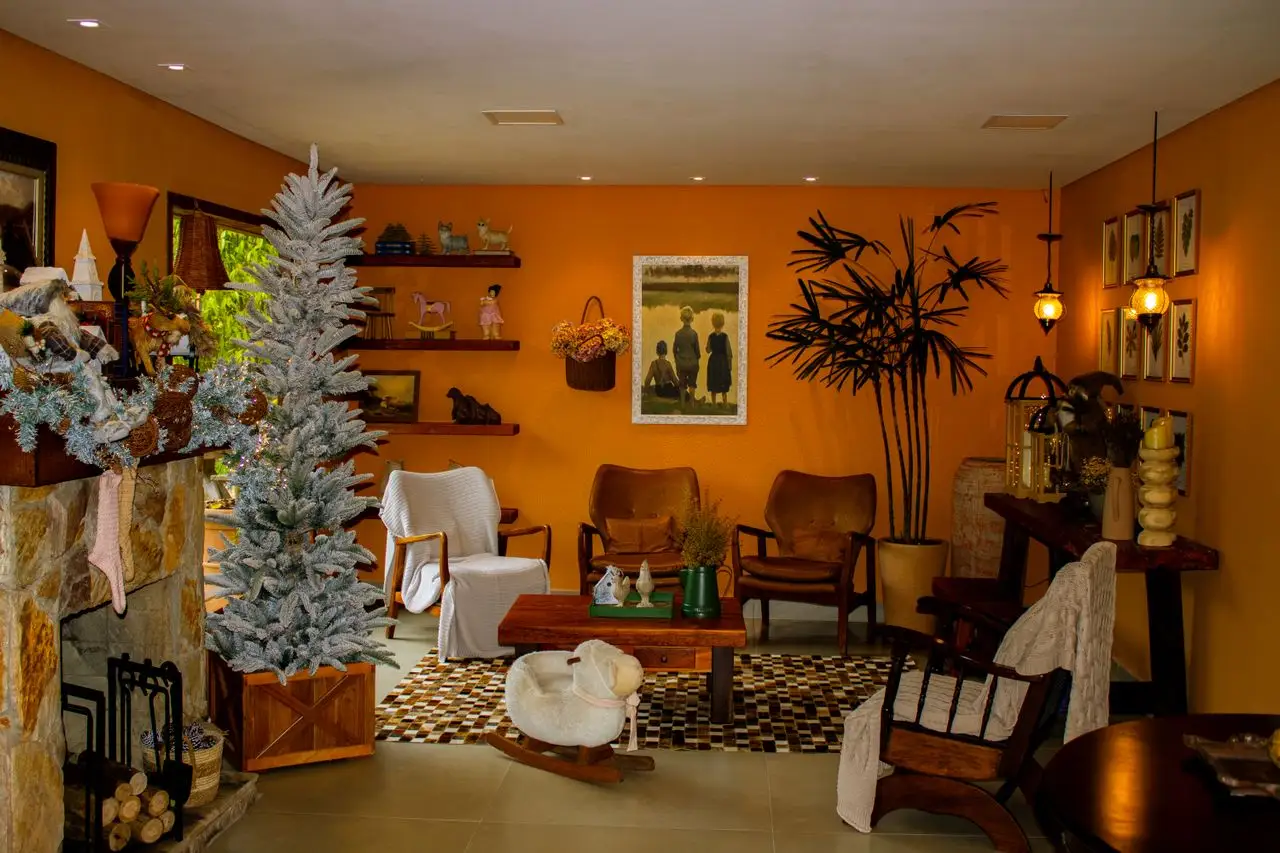 Dicas de Decoração: Transforme Sua Casa com Estilo e Funcionalidade: Sala decorada com luzes aconchegantes, árvore de Natal branca, poltronas de couro, mesa de centro, quadros e tapete xadrez, criando um ambiente acolhedor e funcional.